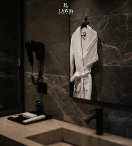 a bathroom mirror with a white suit hanging on a wall at La Onda Hotel Durres in Durrës