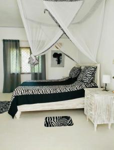 a bedroom with a zebra print bed with a canopy at WHITE Nyumba in Malindi