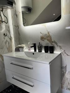 een badkamer met een witte wastafel en een spiegel bij Guest House Eden in Bihać