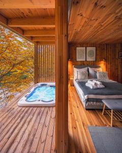 1 dormitorio con 1 cama en una terraza de madera en TreeHouses Noszvaj, en Noszvaj