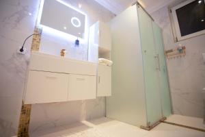 a bathroom with a shower and a sink and a mirror at JQ.APARTMENTS in Accra