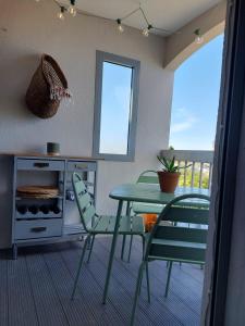 a dining room with a table and chairs and a balcony at La pénate de Saint Cyp - résidence les Frégates vue mer, Piscine in Saint-Cyprien