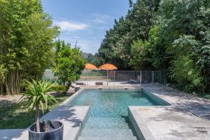 a swimming pool in a yard with a fence and trees at La Madeleine Arles in Arles