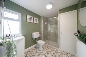 a bathroom with a toilet and a shower and a window at Coorie by the Coast - Arbroath in Arbroath