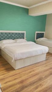 a bedroom with a white bed and a green wall at Khan Plaza in Almaty