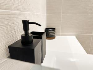 a black soap dispenser sitting on a counter in a bathroom at Luxury 3 Bedroom Apt. Leeds Centre in Leeds