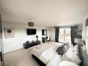 a white bedroom with a large bed and a tv at Luxury 3 Bedroom Apt. Leeds Centre in Leeds