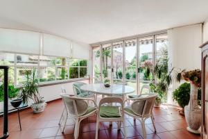 una camera con tavolo, sedie e finestre di Villa La Pergola by Quokka 360 - historic villa with private pool a Magliaso