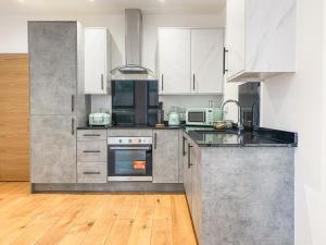 a kitchen with white cabinets and stainless steel appliances at Heathrow Airport Apartments by Elegance Living in Hounslow