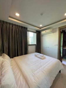 a bedroom with a large white bed with two towels on it at Arcadia beach continental in Pattaya South