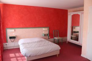 a bedroom with a bed and a red wall at Le Commerce in Dompaire