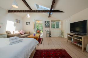 ein Wohnzimmer mit einem Bett und einem Flachbild-TV in der Unterkunft Peaceful, country setting in Suffolk, near coast in Halesworth