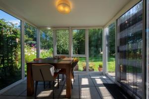 a screened porch with a table and chairs and windows at Peaceful, country setting in Suffolk, near coast in Halesworth