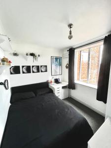 都柏林的住宿－Custom House, 1 room, Dublin 1，一间卧室设有一张黑色的床和一个窗户。