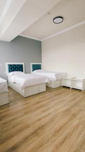 two beds in a large room with wooden floors at Khan Plaza in Almaty