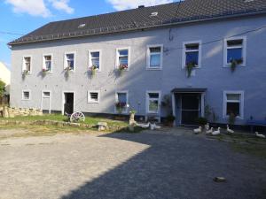 uma grande casa branca com flores nas janelas em Gutshof und Ferienwohnung Proft 