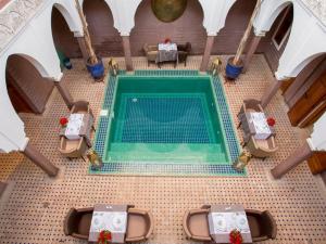 uma vista sobre uma piscina numa sala com mesas e cadeiras em Riad Magda & Spa em Marraquexe