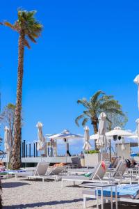 Belvedere Hotel في فلوره: مجموعة من الكراسي والمظلات على الشاطئ