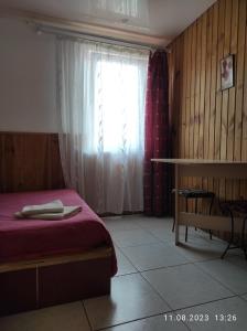 sypialnia z czerwonym łóżkiem i oknem w obiekcie Mini-hotel Kamianets w Kamieńcu Podolskim
