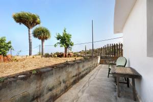 a wooden bench sitting next to a wall with palm trees at Casa Mimí in Las Tricias