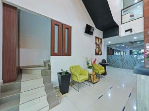 a lobby with yellow chairs and a staircase at Capital O 90841 New One Enigma Hotel in Kuala Lumpur