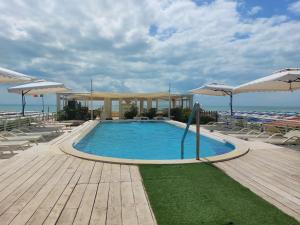 a swimming pool with chairs and umbrellas next to the ocean at Danio beach house in Lido di Camaiore