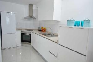 cocina blanca con fregadero y nevera en Bonita vivienda con vistas al mar playaWIFI, en Radazul