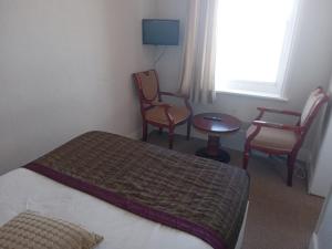 a hotel room with a bed and chairs and a table at Glastonbury Hotel in Eastbourne