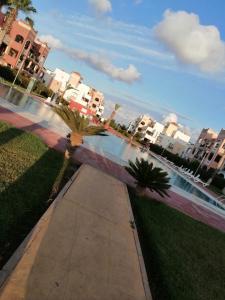 a sidewalk with palm trees next to a body of water at Appartement Saidia avec piscine in Saïdia
