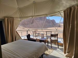 a bedroom with a bed and two chairs in a tent at Mouna Luxury Rum Camp in Wadi Rum