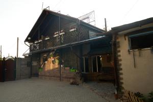 a house with a balcony and stairs in front of it at Argo Guest House in Karakol