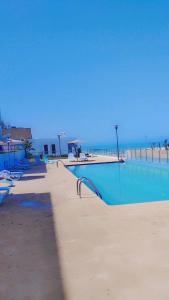 a swimming pool next to a beach with the ocean at Appartement de luxe, front de mer Plage des nations in Salé