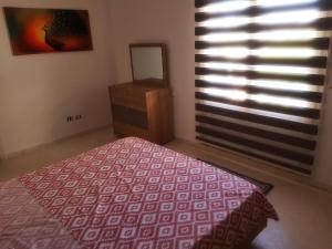 a bedroom with a bed and a dresser and a window at Appartement très coquet dans résidence in Hammamet