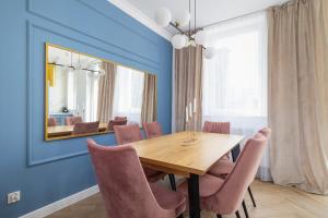 a dining room with a wooden table and pink chairs at Starowiślna Elegant Apartment with Air Conditioning Kazimierz Cracow by Renters Prestige in Krakow