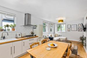 a kitchen and living room with a wooden table at Lovely 2 bed Streatham apt with outside dining in London