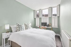 a bedroom with a white bed and windows at Lovely 2 bed Streatham apt with outside dining in London