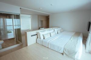 een witte slaapkamer met een groot bed en een badkamer bij Worita Cove Hotel in Na Jomtien