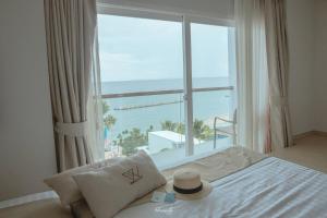 een slaapkamer met een groot raam met uitzicht op de oceaan bij Worita Cove Hotel in Na Jomtien