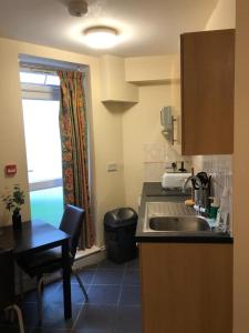 a kitchen with a sink and a table and a window at Cosy 1 Bed Studio in King's Cross in London