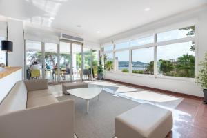 una sala de estar con muebles blancos y ventanas grandes. en Hotel Vibra Riviera en Bahía de San Antonio