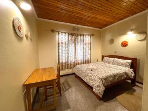 1 dormitorio con cama, mesa y ventana en Toiwo Residence Arusha en Arusha