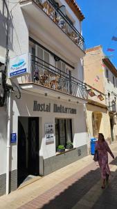 a woman walking down a street in front of a building at Hostal Mediterráneo in Tossa de Mar