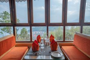 una mesa en un restaurante con almohadas rojas en Summit Namnang Courtyard & Spa, en Gangtok