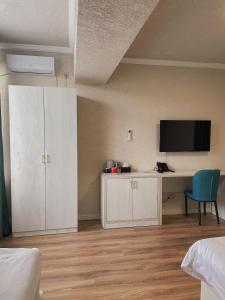 1 dormitorio con escritorio y TV en la pared en Khan Plaza en Almaty