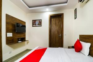 a bedroom with a bed with red pillows and a television at OYO Flagship The Vansh Balaji Hot in Faridabad