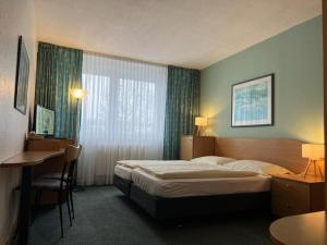 ein Hotelzimmer mit einem Bett, einem Schreibtisch und einem Fenster in der Unterkunft Werrapark Familienresort Hotel Heubacher Höhe in Masserberg