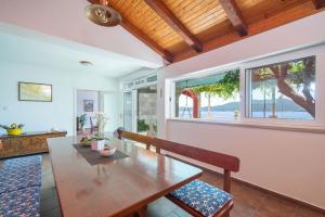 a dining room with a table and a bench and windows at House Planika in Slano