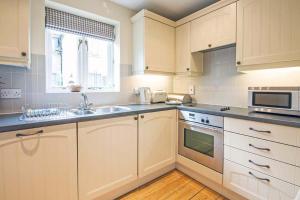 a kitchen with white cabinets and a sink and a microwave at Mill Village 75, Tide Cottage - P in Somerford Keynes