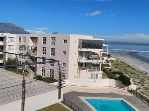 a building with a swimming pool next to the ocean at Cape Beach Penthouse in Cape Town