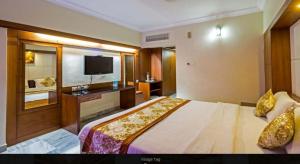 um quarto de hotel com uma cama e uma televisão de ecrã plano em Hotel PLR Grand em Tirupati